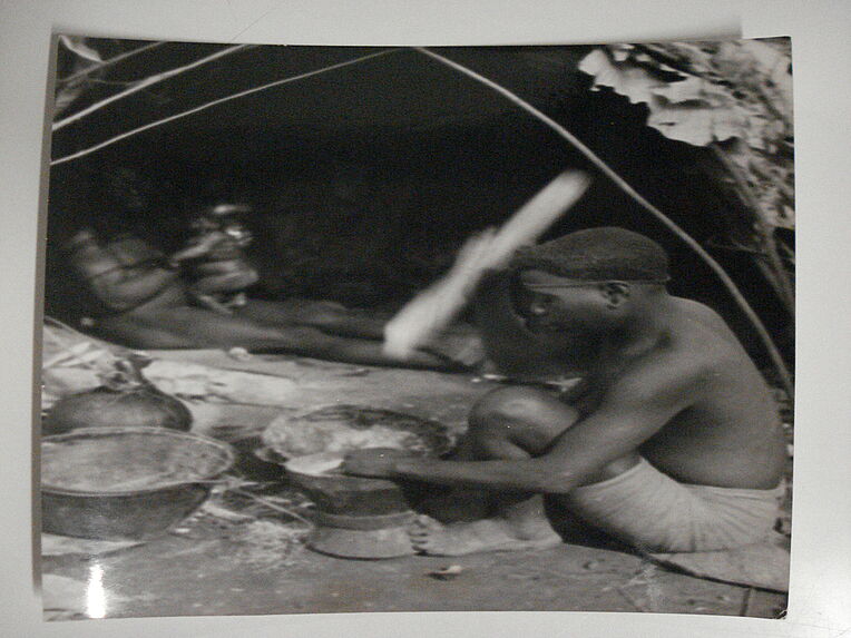 Femme Babenzelé pile du maïs ou du manioc échangé aux noirs