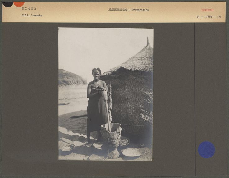 Femme béribéri pilant le mil devant sa hutte