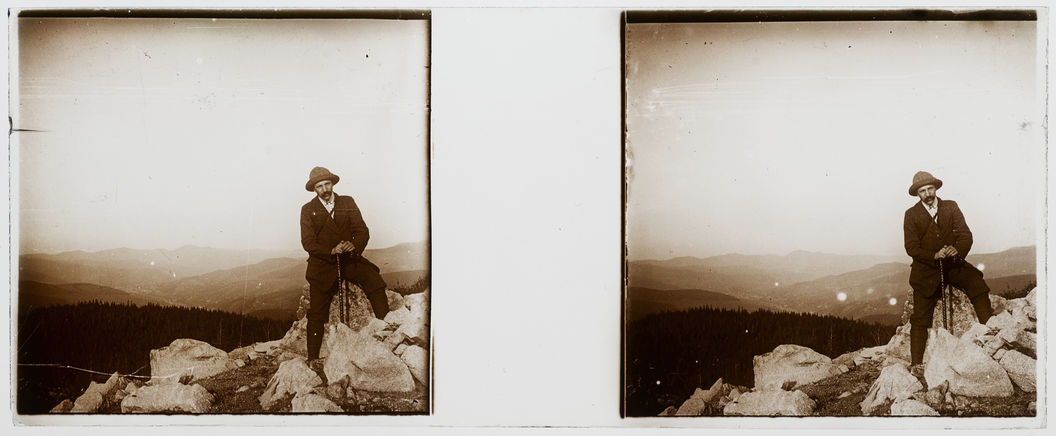 Homme assis sur un rocher face à un panorama montagnard