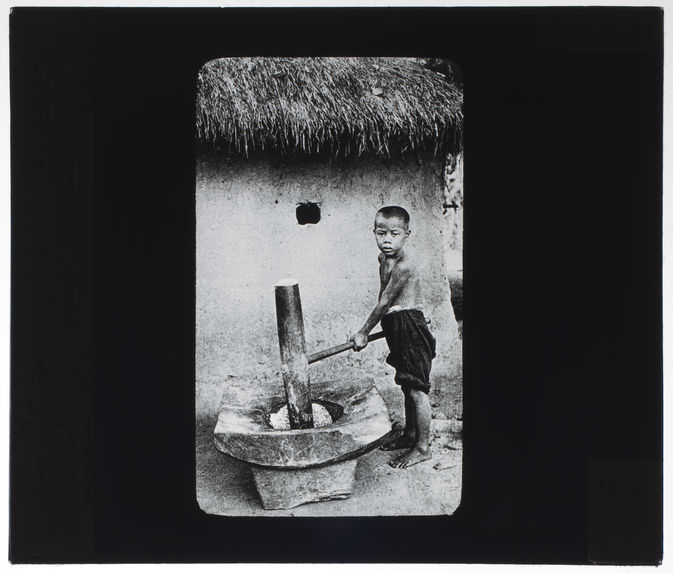 Enfant indigène annamite décortiquant du paddy