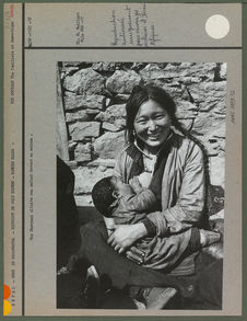 Une Sherpani allaite son enfant devant sa maison