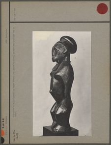 Statuette en bois figurant un homme debout, aux jambes massives, portant des…