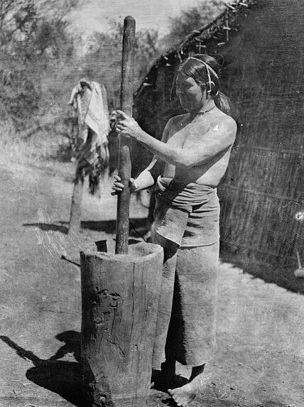 Femme écrasant du maïs dans un mortier