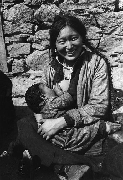 Une Sherpani allaite son enfant devant sa maison
