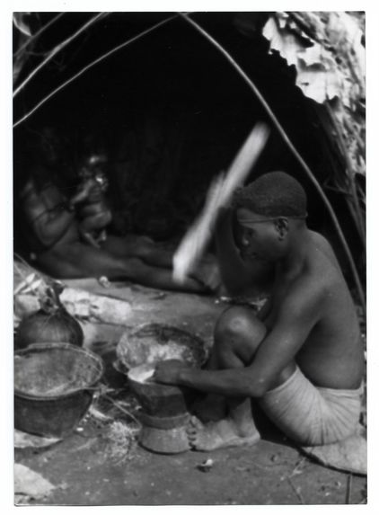 Femme pygmée pilant du maïs échangé aux Noirs