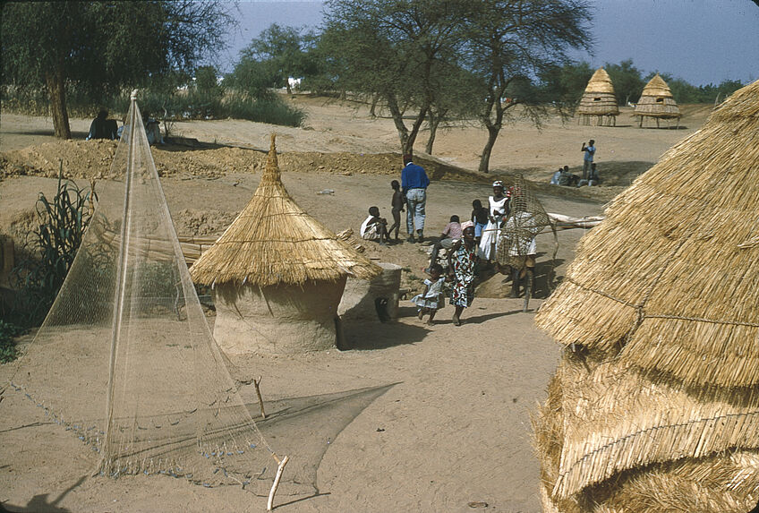 Sans titre [sène de village. Deux huttes et un filet suspendu sur un bâton]