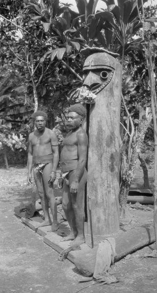 Deux hommes Small Nambas devant tambour à fente dressé